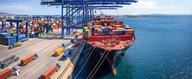 A large container cargo ship is beeing loaded and unloaded in a commercial dock