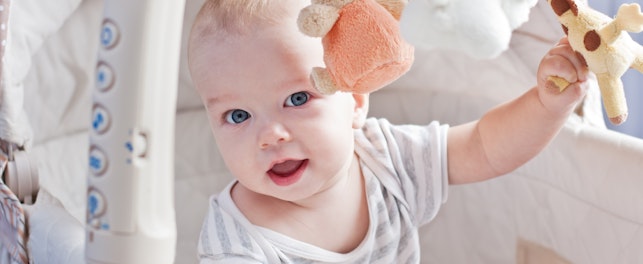 Baby Boy Playing Sitting in the Cradle with Mobile Toy Giraffe