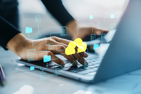 Hands typing on a laptop keyboard with digital icons of folders and a yellow cloud upload symbol, representing cloud data storage and file sharing