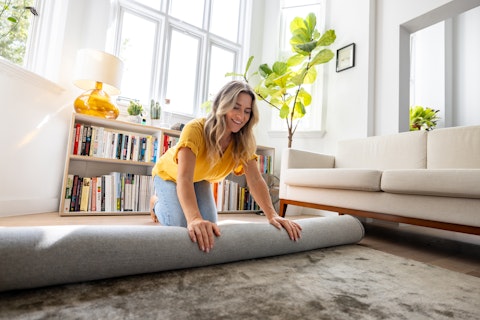 Happy Woman Moving House and Unrolling a Carpet
