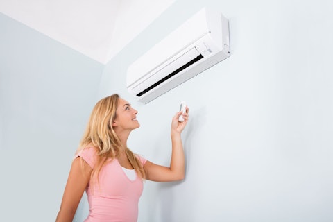 Woman Operating Air Conditioner with Remote