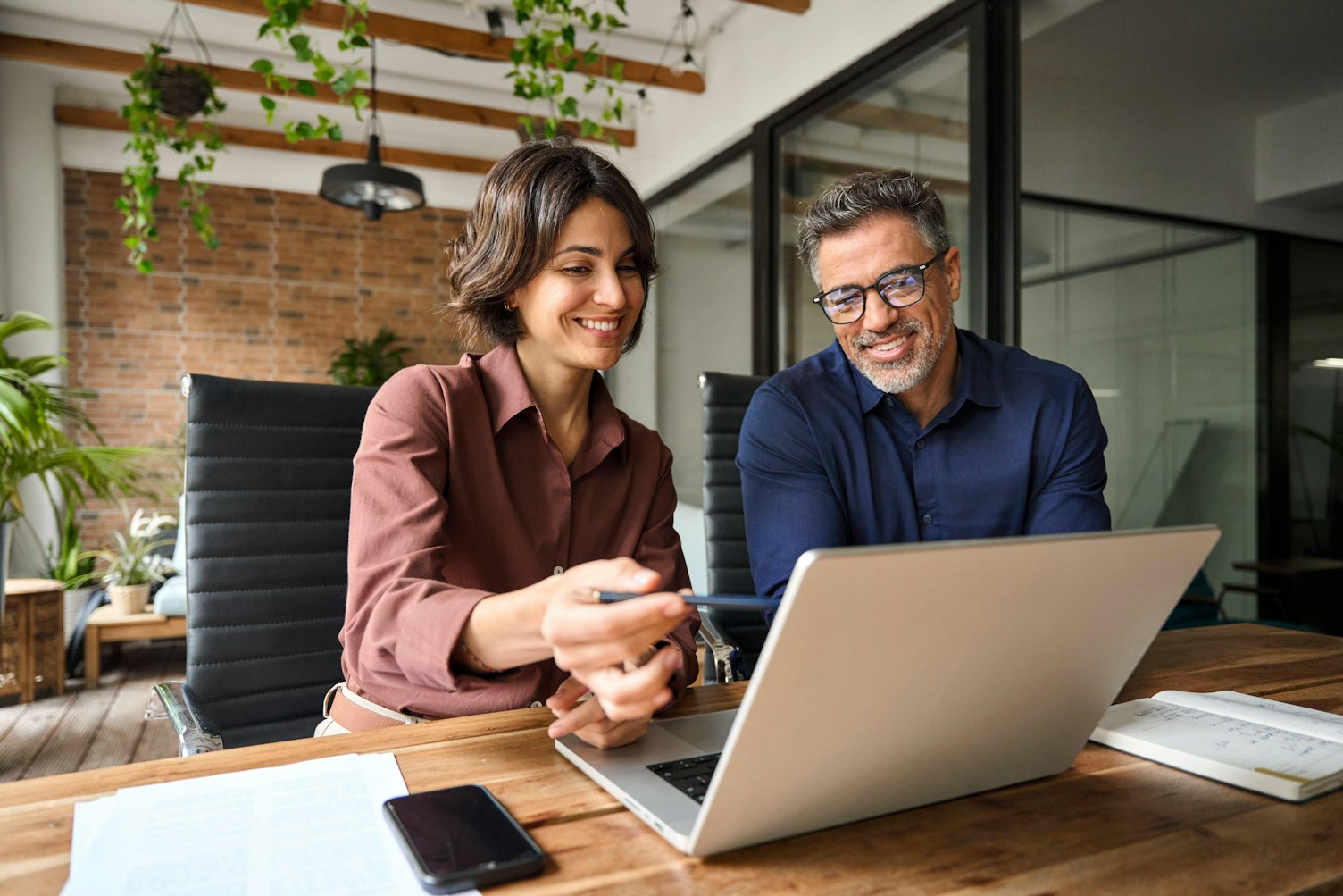 Business team of two executives working together using laptop in office.