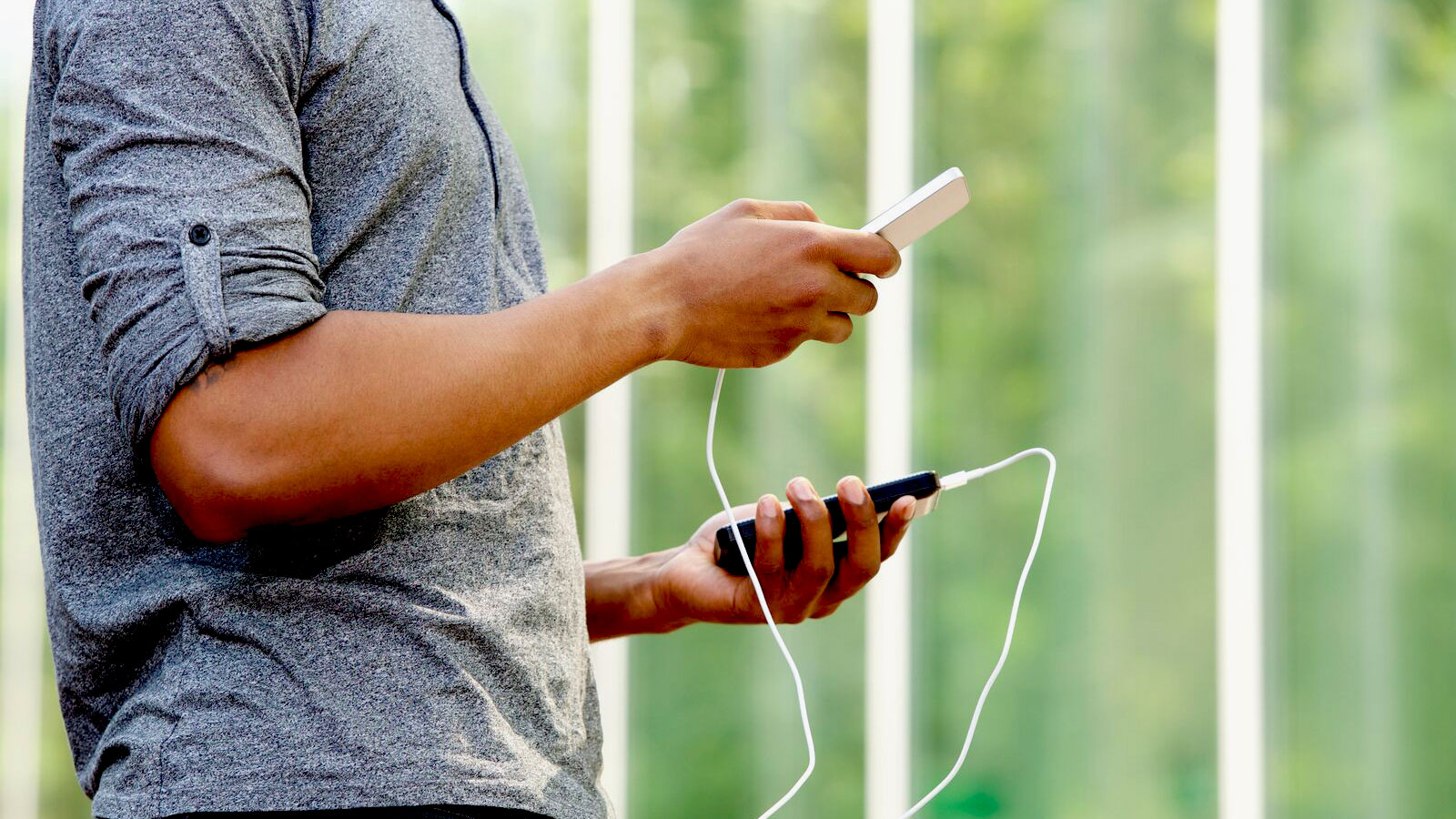 外付けバッテリーとスマートフォンを持つ男性 