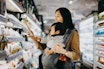 Mother Reading Nutrition Label on Product in a Supermarket