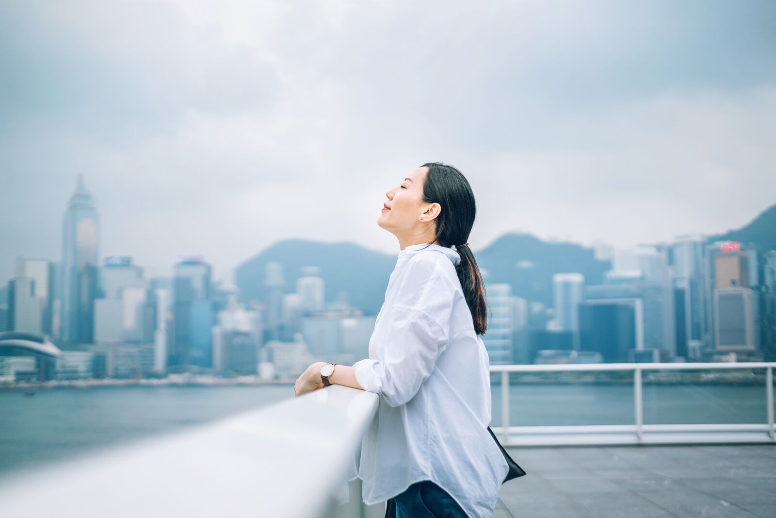 Woman Breathing Fresh Air Against City Background